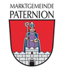 Das Wappen der Marktgemeinde Paternion zeigt ein Schloss mit einer Figur, die einen Stab und ein Buch in der Hand hält, auf einem roten Schild.