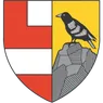 Ein Schild, der in vier Bereiche aufgeteilt ist. Oben links und unten rechts sind rot, oben rechts und unten links weiß. Ein schwarzer Vogel sitzt auf einem grauen Felsen auf der rechten Seite.