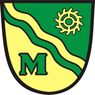 Das Wappen zeigt einen Schild mit einem gelben und grünen Streifen. In der oberen rechten Ecke befindet sich ein gelbes Zahnradsymbol. Der Buchstabe M ist in Grün auf dem Schild geschrieben.