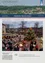 Ein Bild eines Weihnachtsmarktes in Sinabelkirchen, Österreich, zeigt Menschen um ein Lagerfeuer und einen geschmückten Weihnachtsbaum versammelt, mit festlichen Lichtern und Marktständen im Hintergrund.