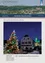 Ein Dorf während der Weihnachtszeit, mit einem gut beleuchteten Weihnachtsbaum vor einem Haus mit einem grün beleuchteten Turm. Der Himmel ist dunkel, und es scheint Nacht zu sein. Das Haus hat eine Uhr an der Wand.