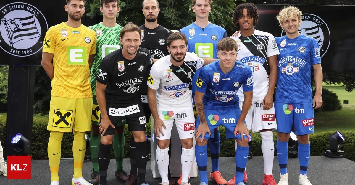 Eine Fußballmannschaft posiert für ein Foto in verschiedenen Teamtrikots. Ein Spieler trägt ein gelbes Trikot, ein anderer ein blaues und die anderen weiße Trikots.