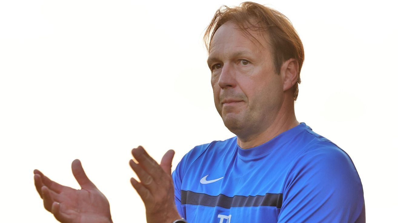 Ein Mann in einem blauen Nike-Shirt mit grauem Streifen und einer Uhr klatscht in die Hände.