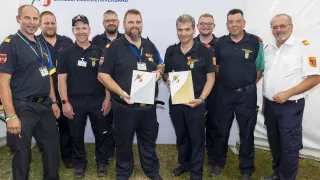 Eine Gruppe von Feuerwehrleuten des Niederösterreichischen Landesfeuerwehrverbandes steht zusammen und hält Auszeichnungen. Sie tragen alle Uniformen und stehen auf Gras.