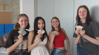 Vier Frauen stehen zusammen, lächeln und halten Geld. Eine hält eine Handvoll Scheine, eine andere ein paar Scheine. Sie scheinen glücklich zu sein.