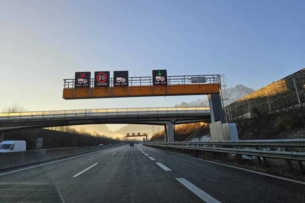 Ein Bild einer Autobahn mit einem Geschwindigkeitsschild und einer Überführung mit einer Brücke. Das Schild zeigt ein Tempolimit von 80 an.