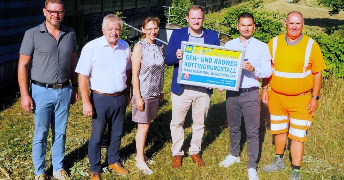 Fünf Personen stehen in einem Grasbereich. Der Mann in der Mitte hält ein Schild mit der Aufschrift Geh-und Radweg Kottingburgstall Marktgemeinde Blindenmarkt.