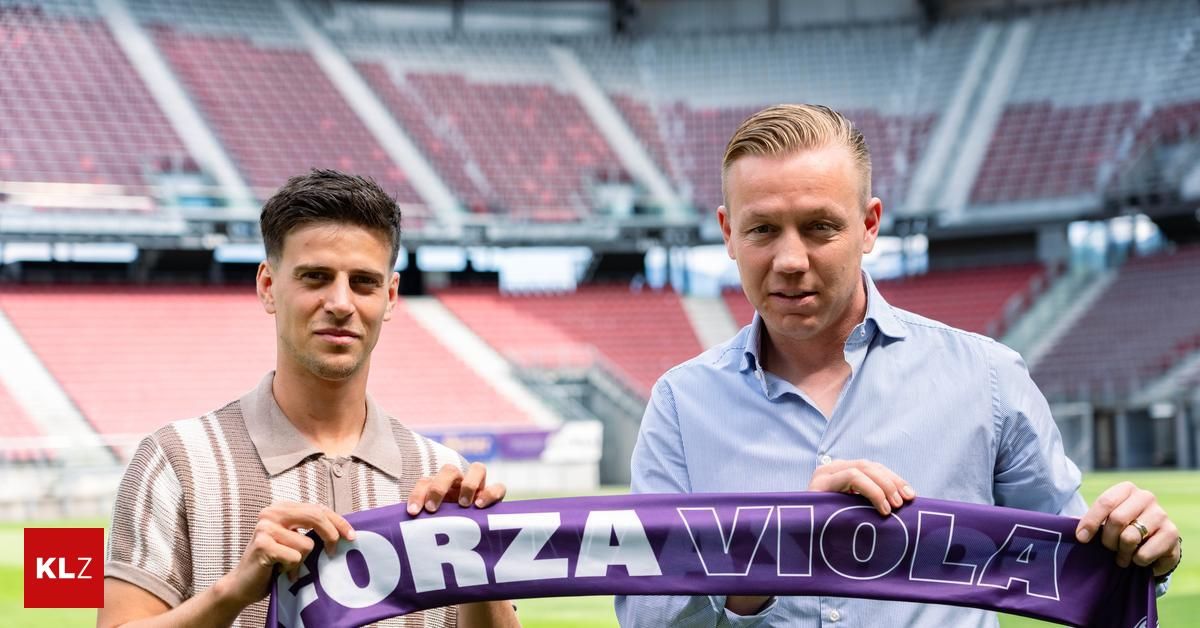 Zwei Männer halten ein lila Banner mit den Worten 'Forza Viola' auf einem Feld vor einem leeren Stadion.