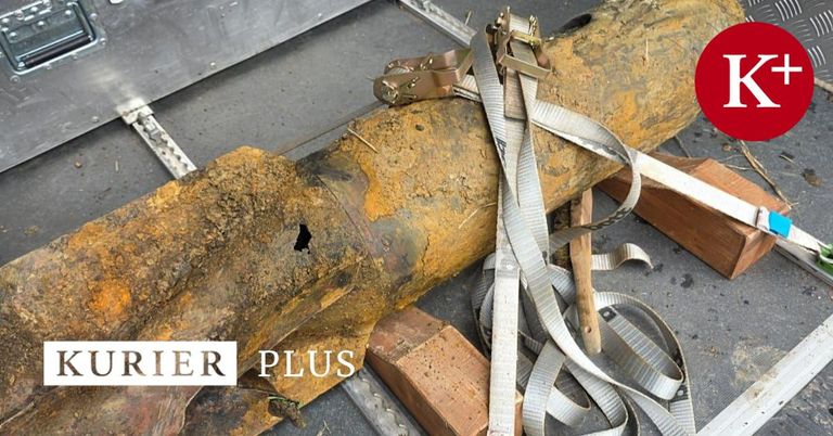 Eingerostete Metallrohre mit einem Loch sind durch Gurte und Klemmen befestigt und liegen auf einem Betonboden mit einem Holzblock und einem Hammer in der Nähe.