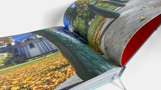 Ein offenes Buch mit einem lebhaften Bild eines grünen Cucumbers auf einer Steinmauer, einem Gebäude im Hintergrund und Herbstblättern auf dem Boden.