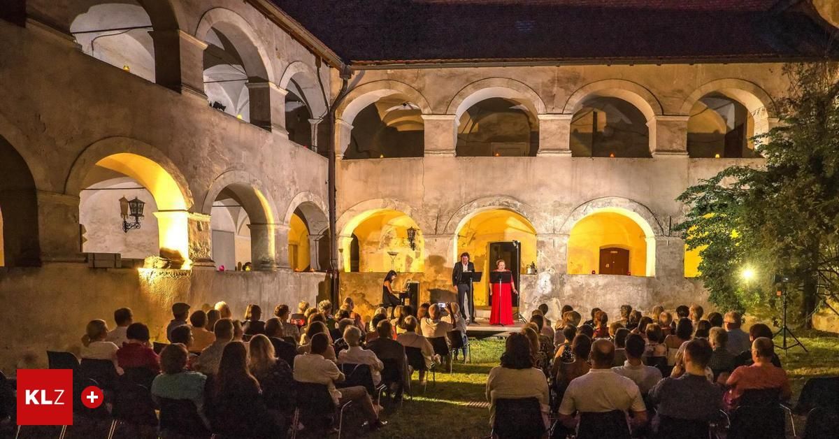 Eine nächtliche Aufführung unter einem alten Innenhof mit Bogenfenstern. Ein Mann und eine Frau singen auf der Bühne, während ein Publikum in Stühlen um sie herum sitzt.