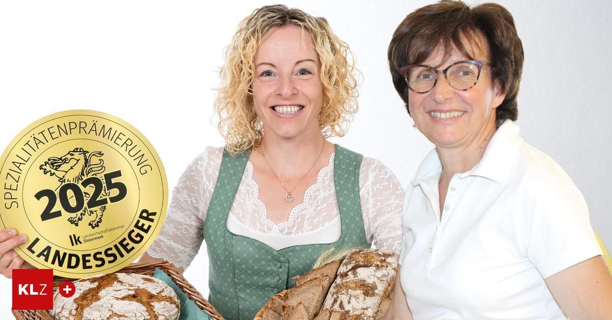 Zwei Frauen lächeln und posieren für ein Foto mit Brot. Eine hält einen Korb mit Brot und die andere ein Brot. Ein goldenes Schild mit dem Wort 'Sieger' im Hintergrund.