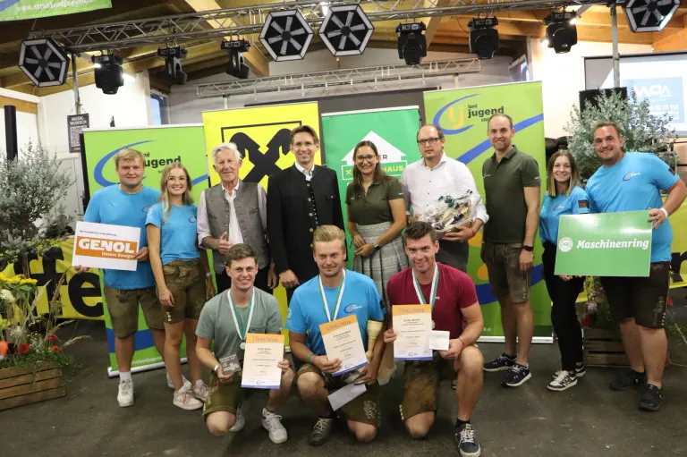 Eine Gruppe von Personen posiert für ein Foto und hält Urkunden in den Händen. Zwei von ihnen knien, und zwei andere stehen hinter ihnen. Sie tragen alle Medaillen um den Hals.