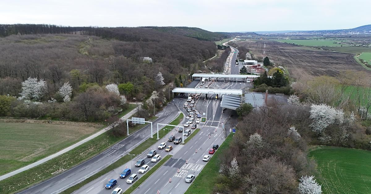 Eine Luftaufnahme einer belebten Autobahn mit Autos, Lastwagen und Lieferwagen, die sich durch Spuren mit Mautstellen und Ampeln bewegen.