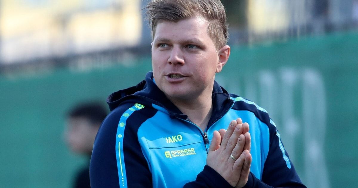 Ein Mann in einem blau-schwarzen Jackett mit Jako und GfFrerer Schriftzug steht im Freien und klatscht in die Hände.