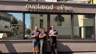 Drei Personen stehen vor einem Restaurant namens Ruckenndorfer. Sie tragen T-Shirts mit der Nummer 40 und scheinen zu feiern.