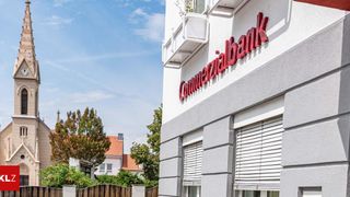 Die Fassade eines Gebäudes mit dem Wort 'Commerzialbank' darauf, mit geschlossenen Jalousien und einem Balkon. Bäume und Häuser im Hintergrund.