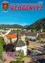 Luftaufnahme der Stadt Gloggnitz mit Bergen, Häusern und einer Kirche. Klarer Himmel, Grünflächen und ein Brunnen im Vordergrund.
