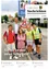 Ein Bild eines lächelnden Mannes in einem Anzug, der mit mehreren Kindern steht. Sie stehen auf dem Bürgersteig mit einem Schild hinter ihnen. Die Kinder tragen Sicherheitswesten.
