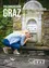 Eine Frau trinkt Wasser aus einem Brunnen in Graz. Der Brunnen befindet sich auf dem St. Radegund-Weg, mit einer Steinmauer und grüner Vegetation. Der Text lautet 'La source des resseux'.
