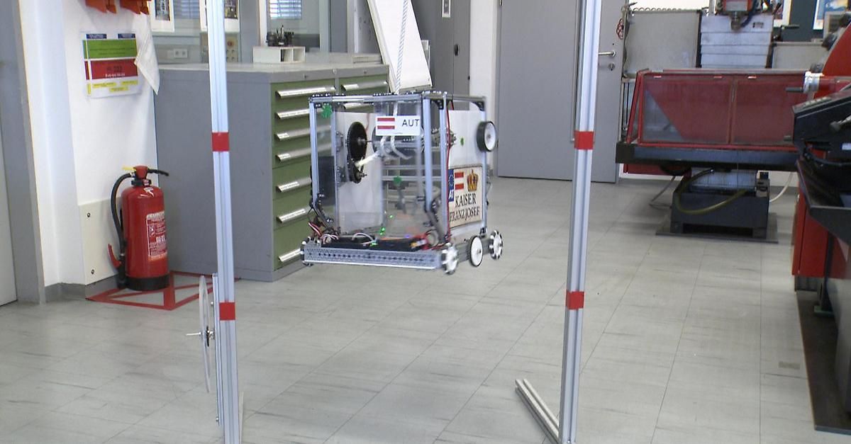 Ein robotisches Gerät mit der Aufschrift aut und Kaiser Franz Josef ist in einem Raum mit Metallstangen aufgehängt.