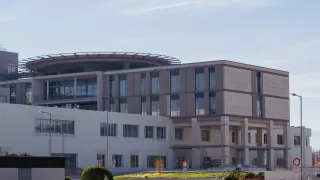 Ein großes Gebäude mit vielen Fenstern und einem runden Dach. Es ist ein zweistöckiges Gebäude mit einem gepflegten Vorgarten.