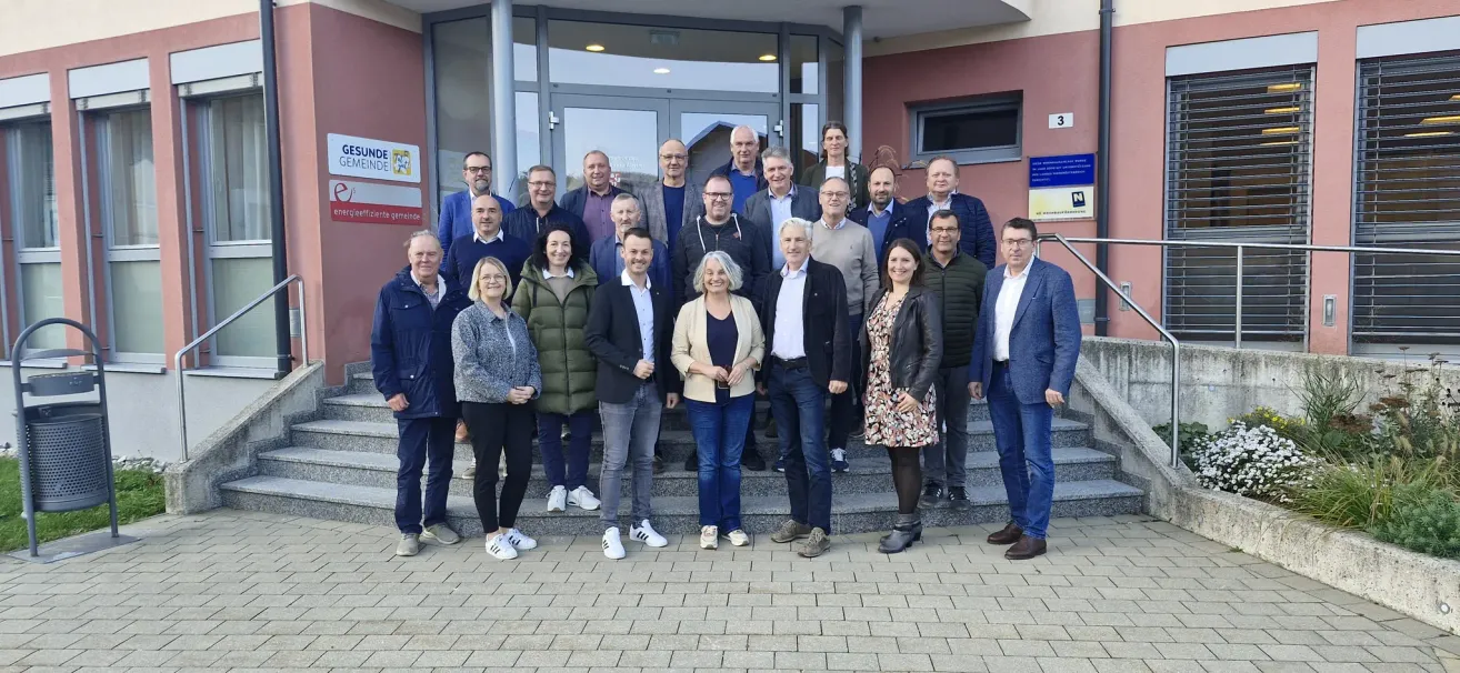 Eine Gruppe von Erwachsenen, sowohl Männer als auch Frauen, in formeller und lässiger Kleidung, posiert für ein Foto auf den Stufen vor einem Gebäude.