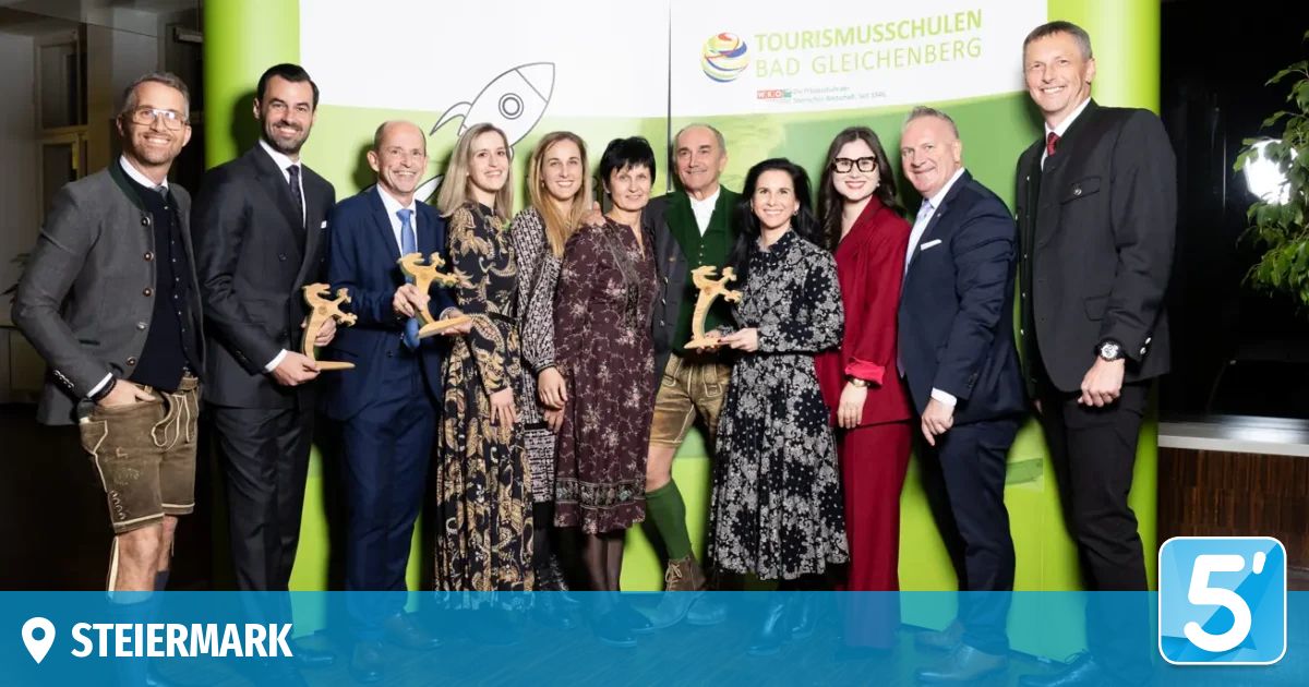 Eine Gruppe von Personen in formeller Kleidung posiert für ein Foto mit Auszeichnungen vor einem grünen Hintergrund mit einer Raketenillustration.