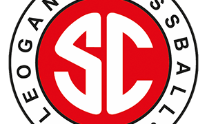 Ein kreisförmiges Emblem mit einem weißen S und C in einem roten Kreis, umgeben von 'Teogang Fussball' und dem Jahr '1964'. Der Hintergrund ist schwarz.