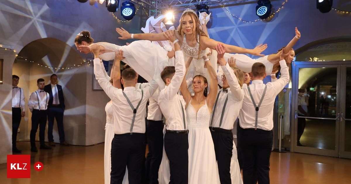 Eine Gruppe von Menschen hebt eine Braut in einem weißen Kleid. Sie stehen auf einem hölzernen Boden mit blauer Beleuchtung darüber.