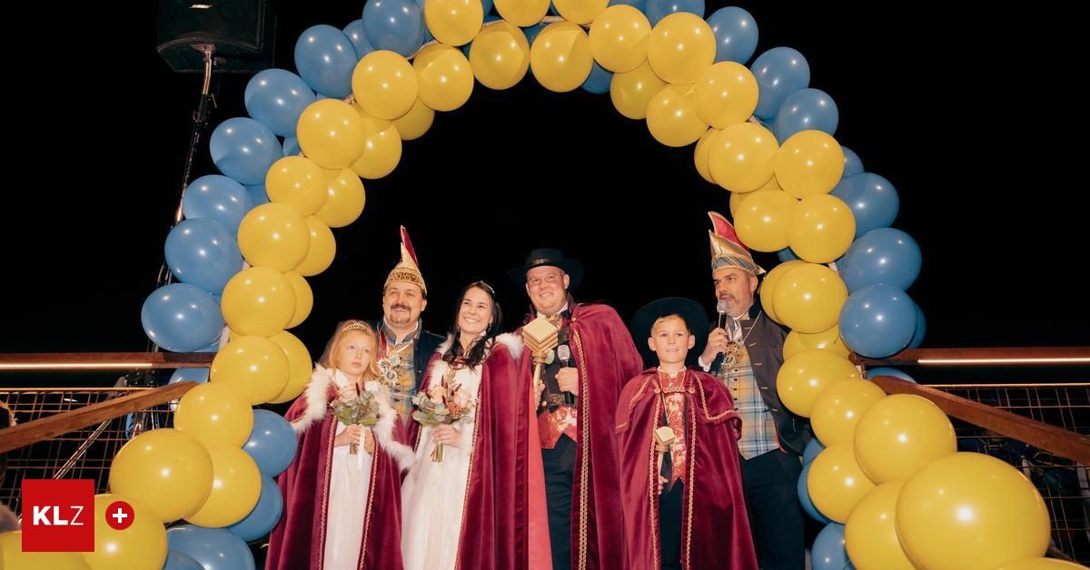 A group of adults and children dressed in costumes, standing under a balloon arch, possibly for a photo shoot.
