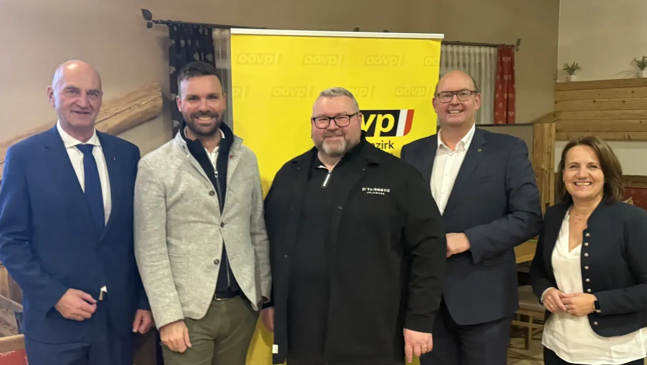 Three men stand in front of a yellow banner with the letters 'VP' and 'oovp'. They are smiling and appear to be posing for a photo.