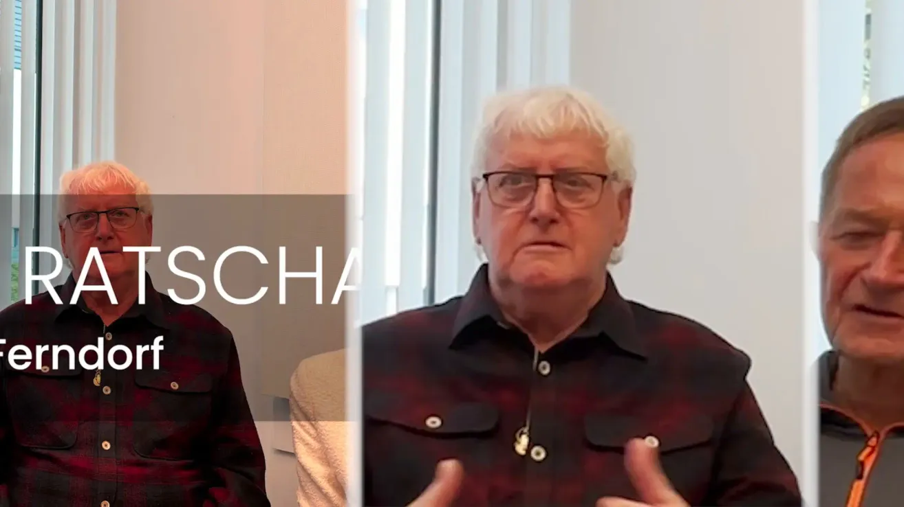 An older man with white hair and glasses speaks into a camera. He gestures with his hands and appears serious. The background shows a split image with text overlay reading 'SCHA'.