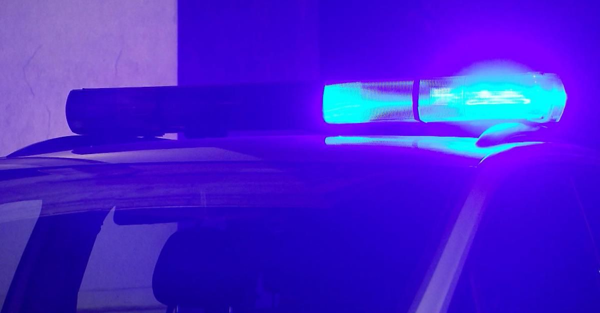 A car dashboard is lit with a blue light, possibly from a police vehicle. The light is on top of a windshield wiper.