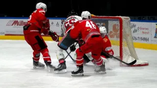 Four hockey players in red uniforms are on an ice rink. They are all wearing helmets, gloves, and skates. One player is bent over while another player is holding a hockey stick.