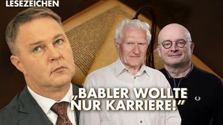 Three men pose in front of an old book. The man on the left wears a suit and tie. The middle man wears a white shirt. The man on the right wears glasses and a black shirt.