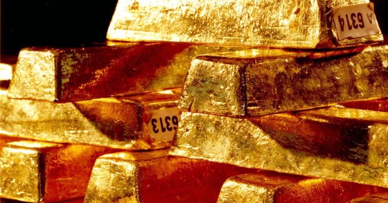 Ein Stapel Goldbarren mit einer Aufschrift 'ELEG' auf einem von ihnen, die ihre glänzende, reiche goldene Farbe und die komplizierten Texturen zeigen.