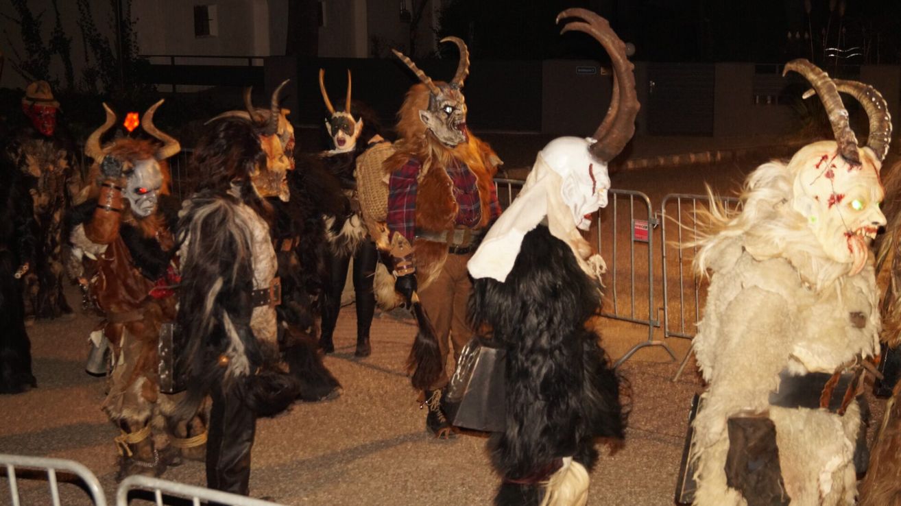 Eine Gruppe von Menschen in Tiermasken und Kostümen geht bei Nacht. Sie nehmen möglicherweise an einem Festival teil.