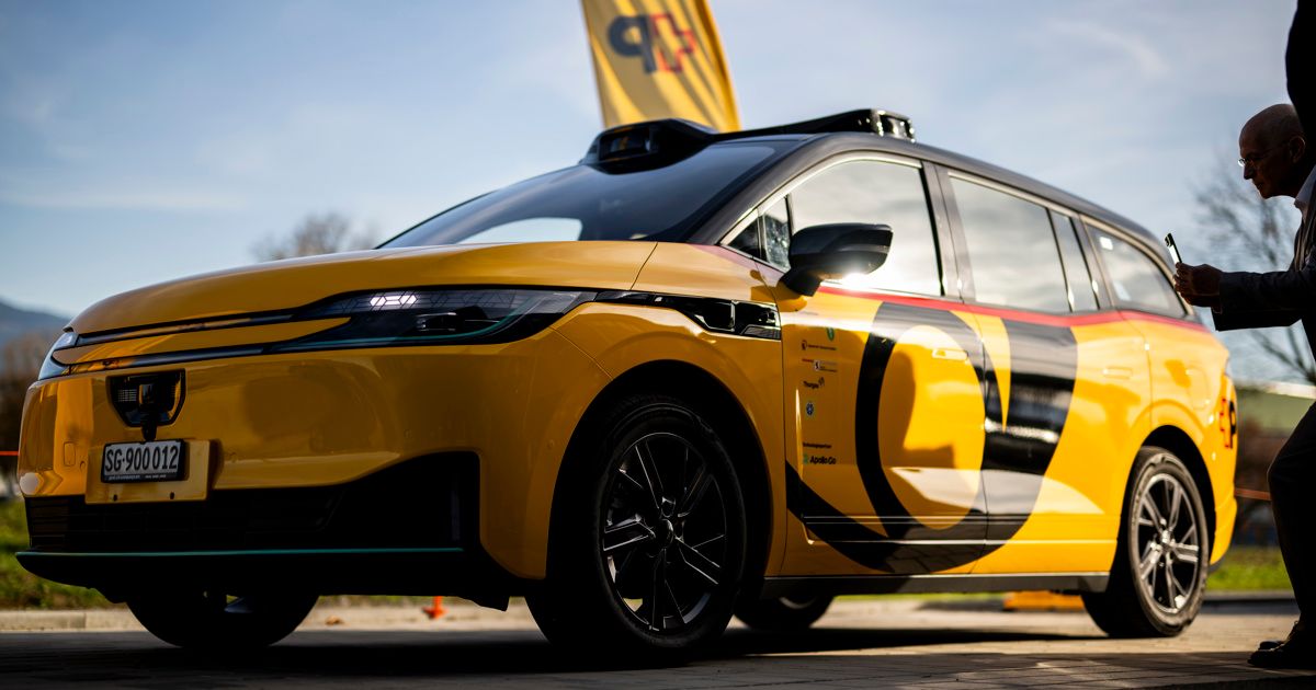 A yellow electric car is parked on a paved surface. It has a black roof and distinctive yellow and black designs on its sides.