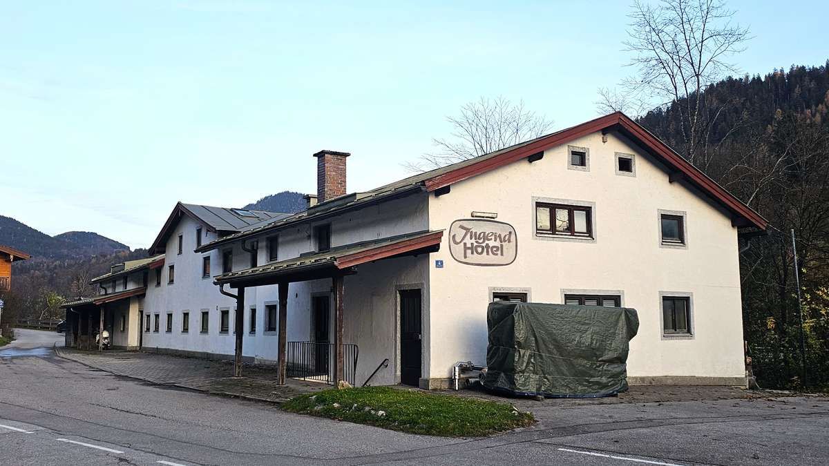 The image shows a hotel with a chimney, a covered car, and a pathway in front of it.