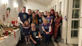 A group of people stand in a hallway with a festive atmosphere, wearing matching shirts and posing for a photo.