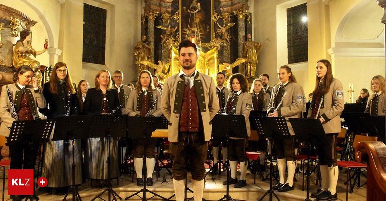 Eine Band tritt in einer Kirche auf, mit mehreren Musikern, darunter ein Mann in traditioneller Kleidung, der vor einem goldenen Altar Instrumente spielt.