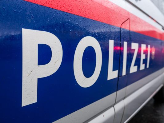 Nahaufnahme eines blau-roten Polizeiwagens mit 'POLIZEI' in weißer Schrift. Der Wagen ist nass.