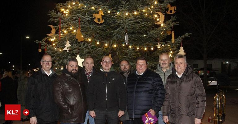 Eine Gruppe von Männern posiert für ein Foto vor einem geschmückten Weihnachtsbaum in der Nacht.