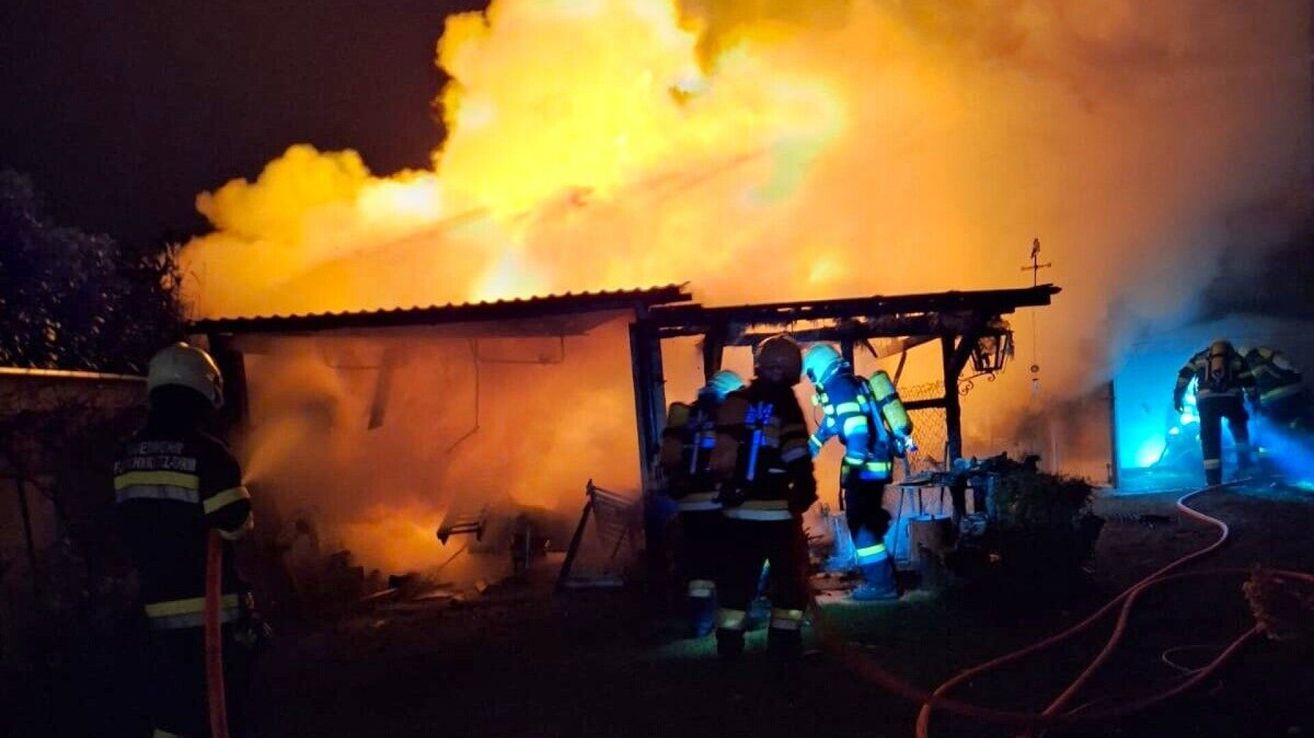 Feuerwehrleute bekämpfen ein großes Feuer, das ein Gebäude bei Nacht verschlingt, mit Rauch und Flammen, die dramatisch aufsteigen.