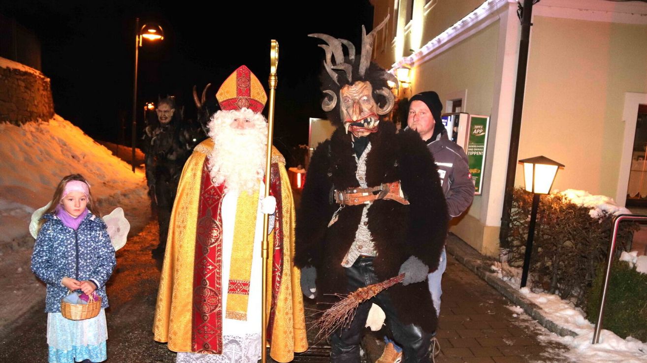 Ein Mann als Teufel verkleidet und ein anderer als Heiliger gehen bei Nacht draußen.