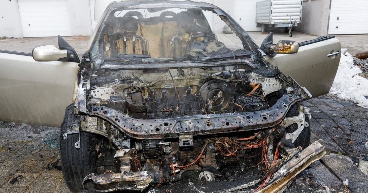 Das ausgebrannte Fahrzeug hat Teile der Vorderseite verloren, mit sichtbaren Schäden am Motor und an den Kabeln.