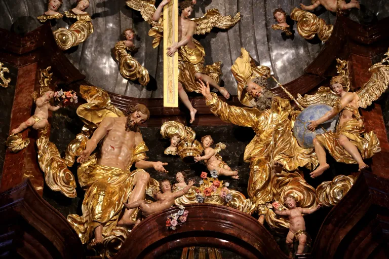 Eine goldene Statue von Jesus Christus am Kreuz wird von Cherubinen und Engeln flankiert. Ein älterer Mann hält eine Weltkugel, und Cherubinen spielen um Blumen herum.