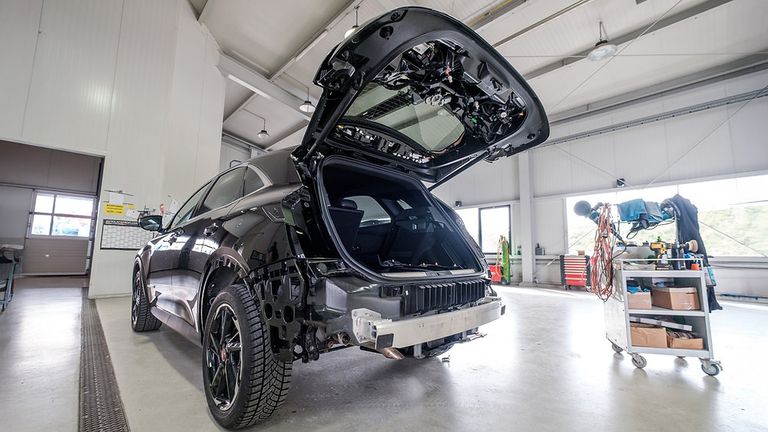 Ein schwarzer Wagen mit offenem Kofferraum in einer Garage, der seinen Heckstoßfänger und Innenraumkomponenten zeigt.