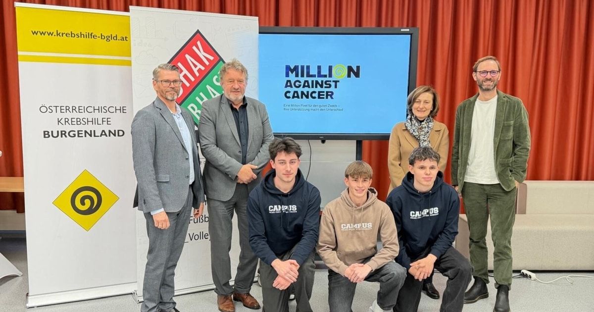 Eine Gruppe von Menschen in formeller Kleidung und Kapuzenpullovern posiert für ein Foto vor einem Bildschirm, der Million gegen Krebs zeigt.